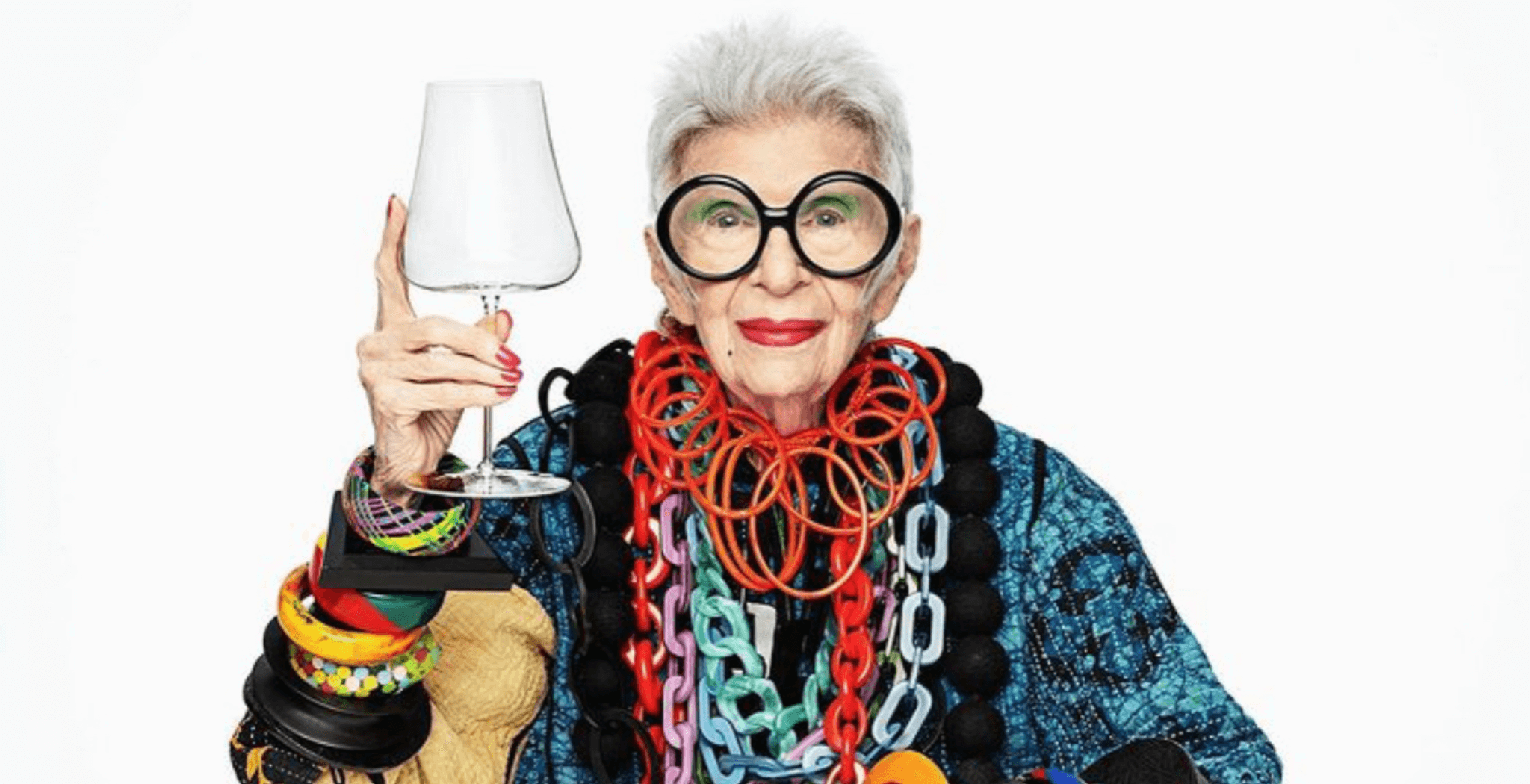 An old women, Iris Apfel is holding a wineglass
