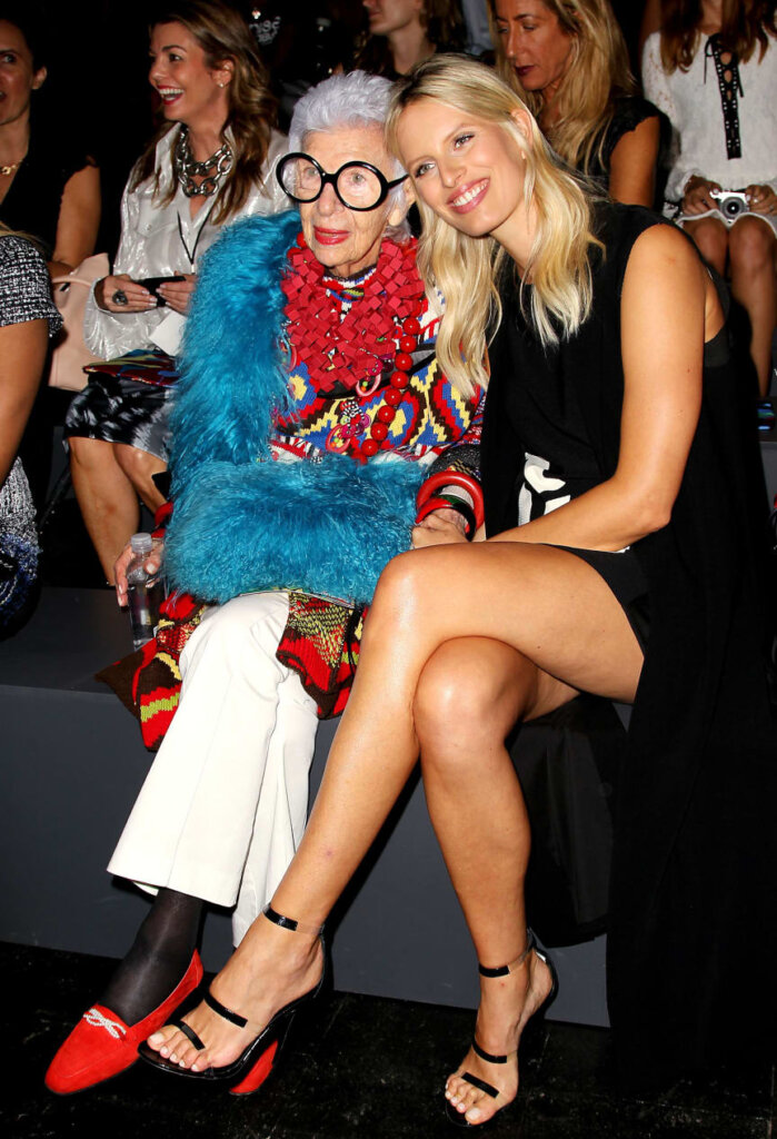 an old woman, Iris Apfel is sitting with a young woman, both laughing