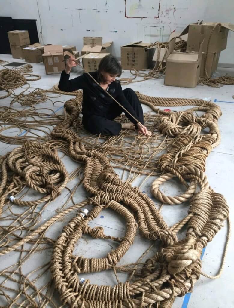 A women, Susan Beallor-Snyder is working on an artpiece, made out of heavy strings