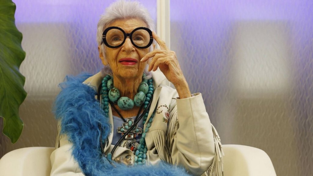 an old woman, Iris Apfel is sitting in a white chair