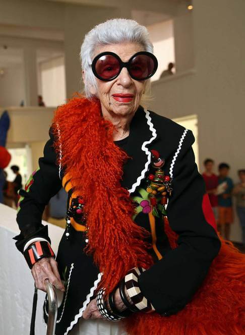 Iris Apfel with huge sunglases and a red featherboa