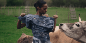 a woman wearing denim looking at a cow in REVOLVE: A Story About Denim Couture and Environmental Awareness