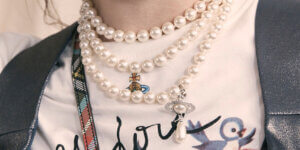 Layered pearl necklaces with Vivienne Westwood Orb pendant over graphic T-shirt, blending classic and punk fashion styles.