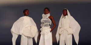 Three Black models wearing Afro-futurist white sculptural garments by African designers at Berlin Fashion Week 2025, symbolizing sustainable innovation and cultural identity.