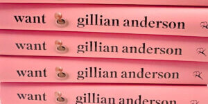 Stack of pink hardcover books titled Want by Gillian Anderson, featuring a minimalist design with a pearl illustration in the center.