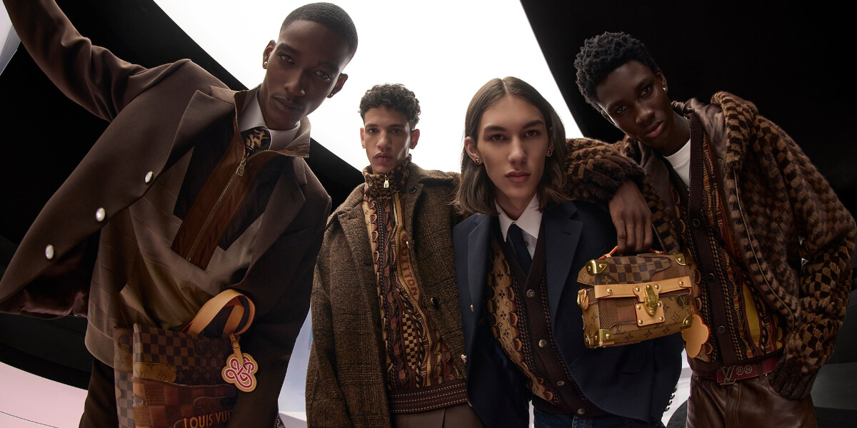 Four models wearing layered fall menswear in rich brown tones featuring tailored jackets, textured knits, and monogram accessories from Louis Vuitton’s Fall/Winter collection, representing timeless luxury and mindful fashion choices.