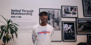 Atiba Jefferson standing in front of his “United Through Skateboarding” photo exhibit in collaboration with Vans, featuring portraits of skaters and community moments.