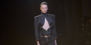 Model walking the runway at Berlin Fashion Week wearing a black cut-out look from Laura Gerte’s AW26 “Deviant Defiant” collection exploring the female villain archetype.