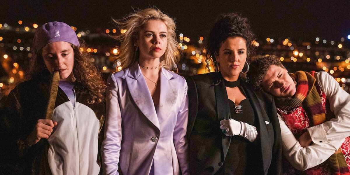 Group of teenage girls from Derry Girls laughing together in school uniforms, representing strong female friendship and girlhood in Northern Ireland