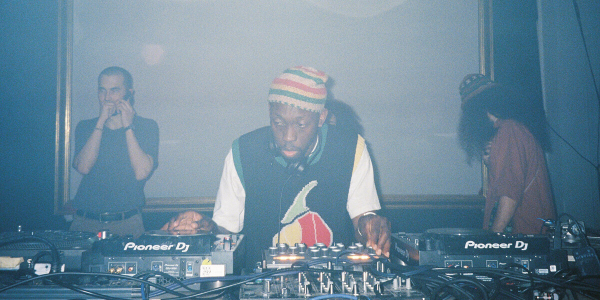 Touching Bass 10th anniversary event in Berlin with SHUSH, featuring Errol, Maxwell Owin, and dancers gathered around the soundsystem celebrating community-driven nightlife and Black diasporic music culture