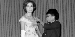 American fashion designer Ann Lowe reviewing sketches of elaborate formal and bridal gowns in her studio.