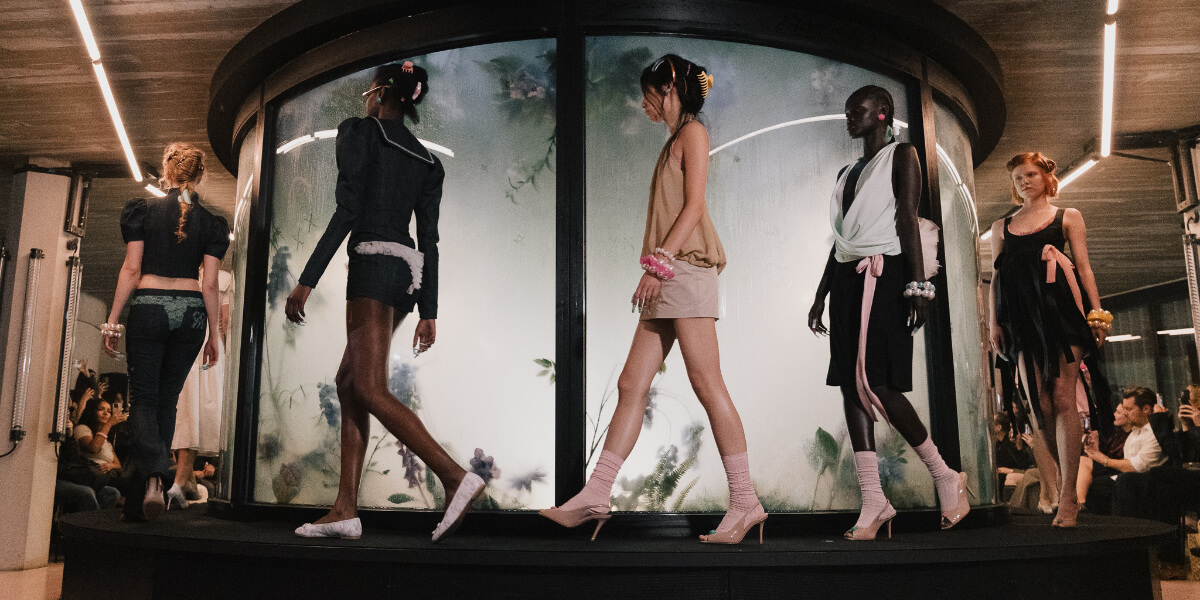 Model wears Clara Colette Miramon Spring/Summer 2027 runway look at Berlin Fashion Week, showcasing feminine tailoring, tropical florals, lace details, and contemporary womenswear.