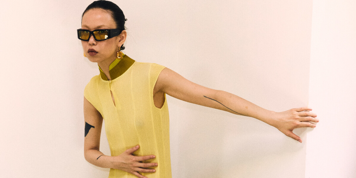 Model wears William Fan Spring/Summer 2027 "EXCHANGE" runway look at Berlin Fashion Week, showcasing contemporary tailoring, upcycled fabrics, and travel-inspired design.