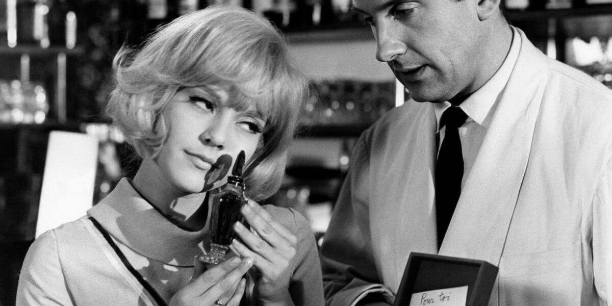 Woman and man examining a perfume bottle in a vintage black-and-white scene