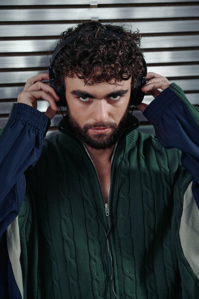 Arda Saatçi wears a green sweater and headphones in TITLE Magazine’s Berlin Psycho fashion editorial