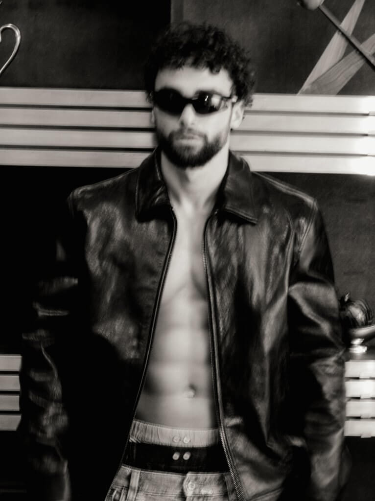 Arda Saatçi shows his six-pack abs while posing shirtless in a leather jacket, sunglasses, boxers and jeans for TITLE Magazine’s Berlin Psycho fashion editorial