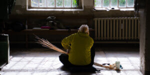 Fashion designer participating in a sustainable fashion and traditional craft residency at Werkhaus Stöckle in Gerswalde, Germany, working with natural materials in a historic workshop.