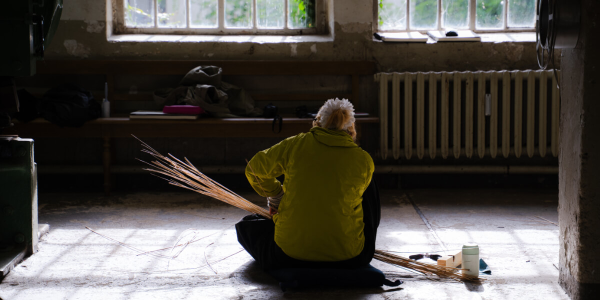 Fashion designer participating in a sustainable fashion and traditional craft residency at Werkhaus Stöckle in Gerswalde, Germany, working with natural materials in a historic workshop.