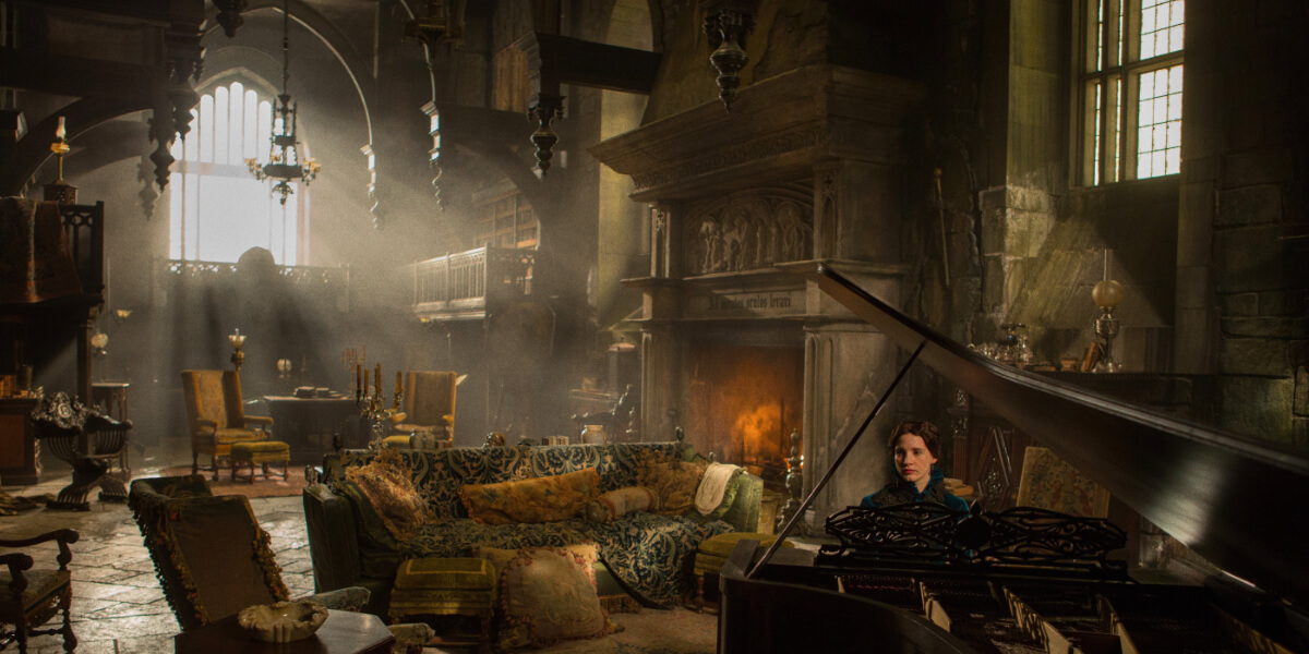 Crimson Peak gothic mansion interior with a woman playing piano in a dark, candlelit room, a scene from Guillermo del Toro’s 2015 film