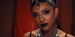 Alewya portrait with dramatic black eyeliner, dark lipstick, gold hoop earrings and statement silver jewelry, featured in an article on autumn music discoveries and alternative R&B artists.